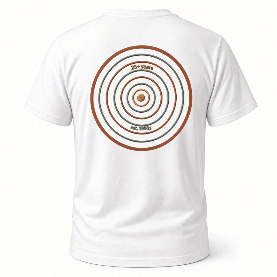 A white t-shirt, back view, with the rings mark printed in orange, green, and gold, reading 25+ years and est. 1990s